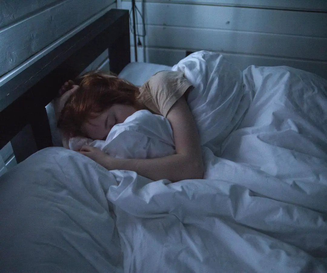 A woman sleeping with white bedding.